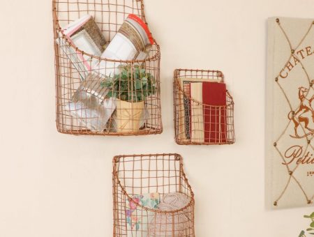 three copper wall baskets that each contain variety of products, perfect for storing office materials and books.