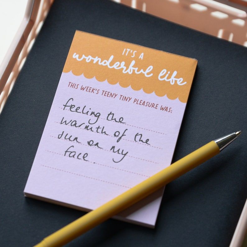 a mini notepad, with pen, that reads 'it's a wonderful life, this weeks teeny tiny pleasure was:' with space to write a sentence or two.