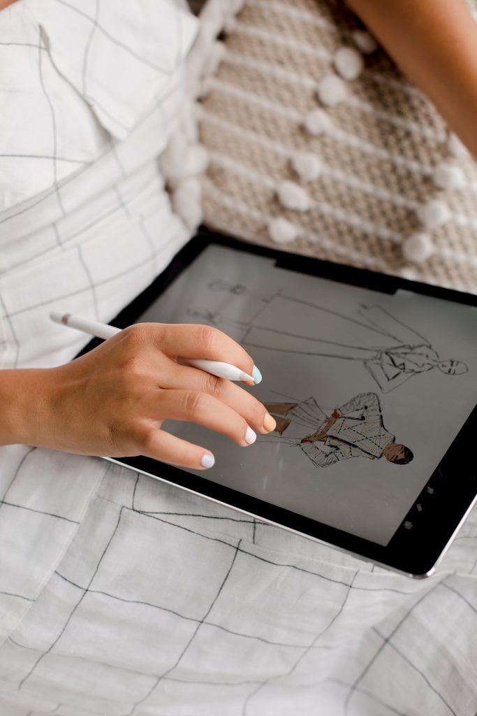 close up of a person using a tablet to create a fashion design drawing.